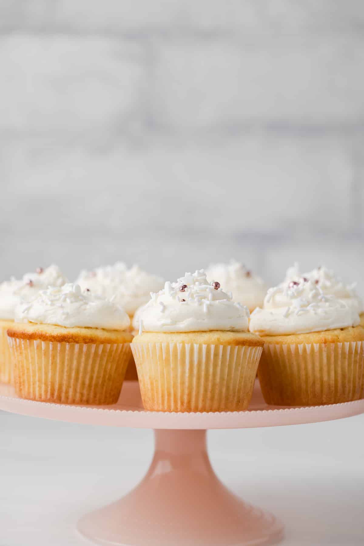 Almond cupcakes on a pink cake stand.