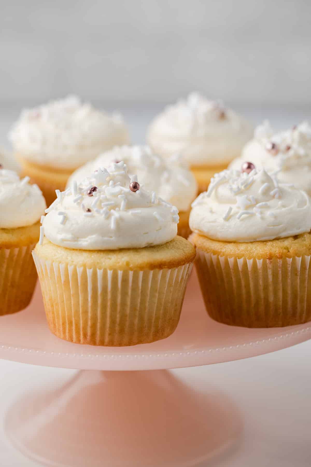 Close up of almond cupcakes on a pink cake stand.