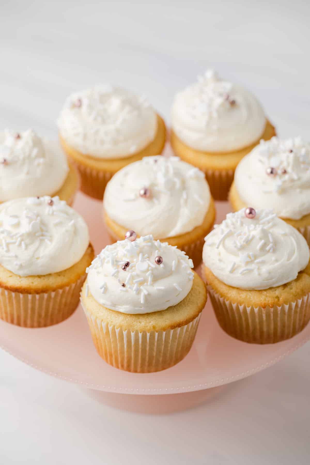 High angled view of almond cupcakes on a pink serving platter.