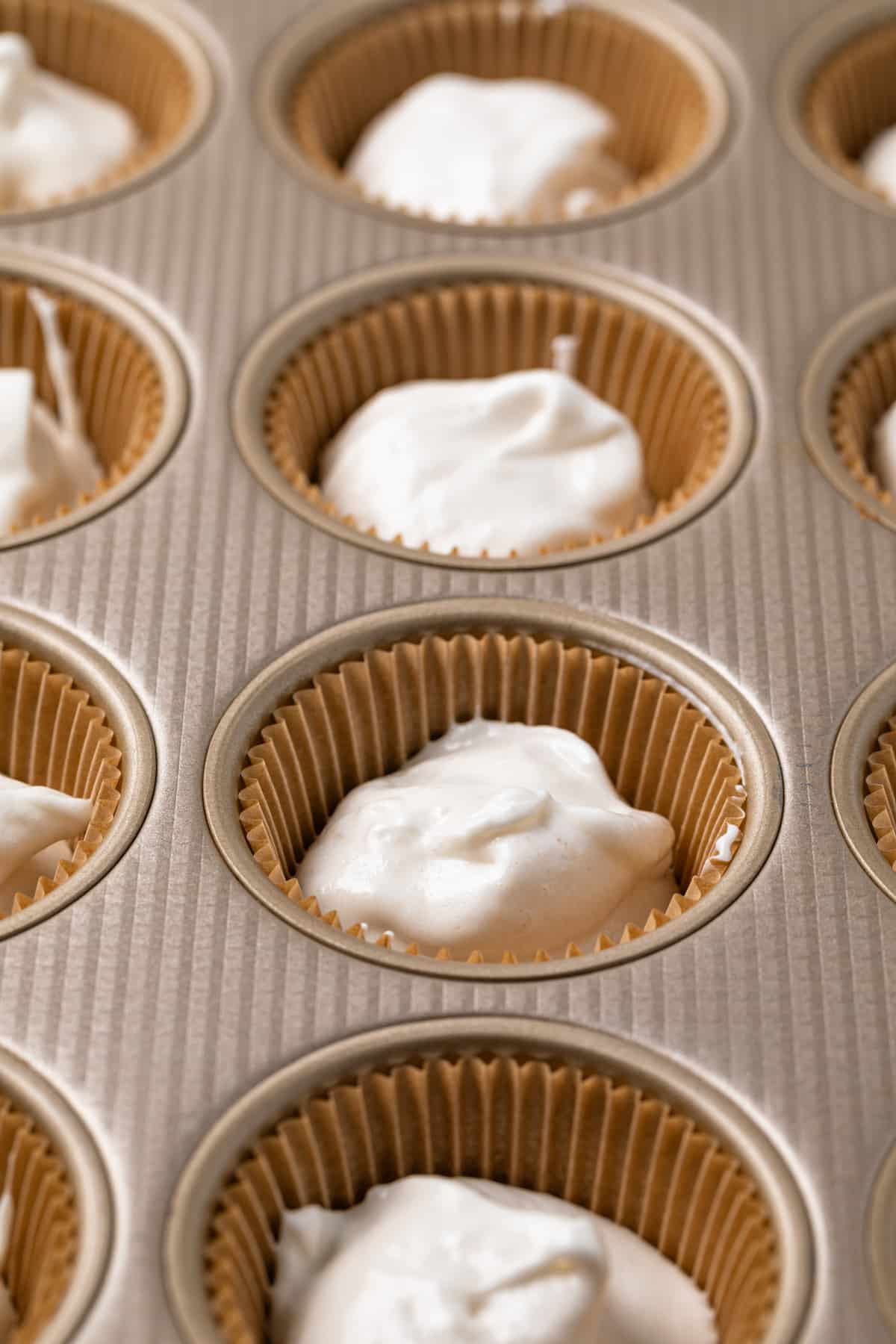 Unbaked cupcake batter in a lined muffin pan.