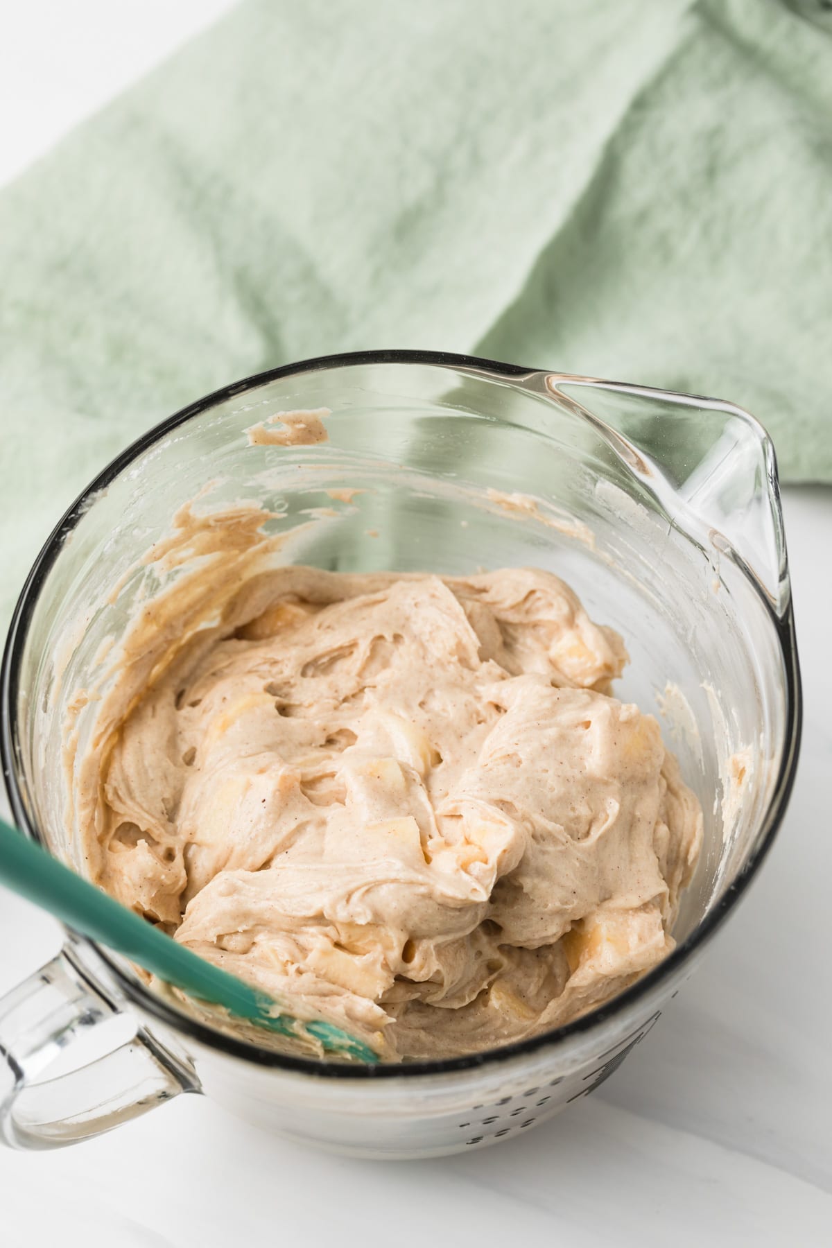 batter for apple bread in glass bowl with green napkin and teal spatula