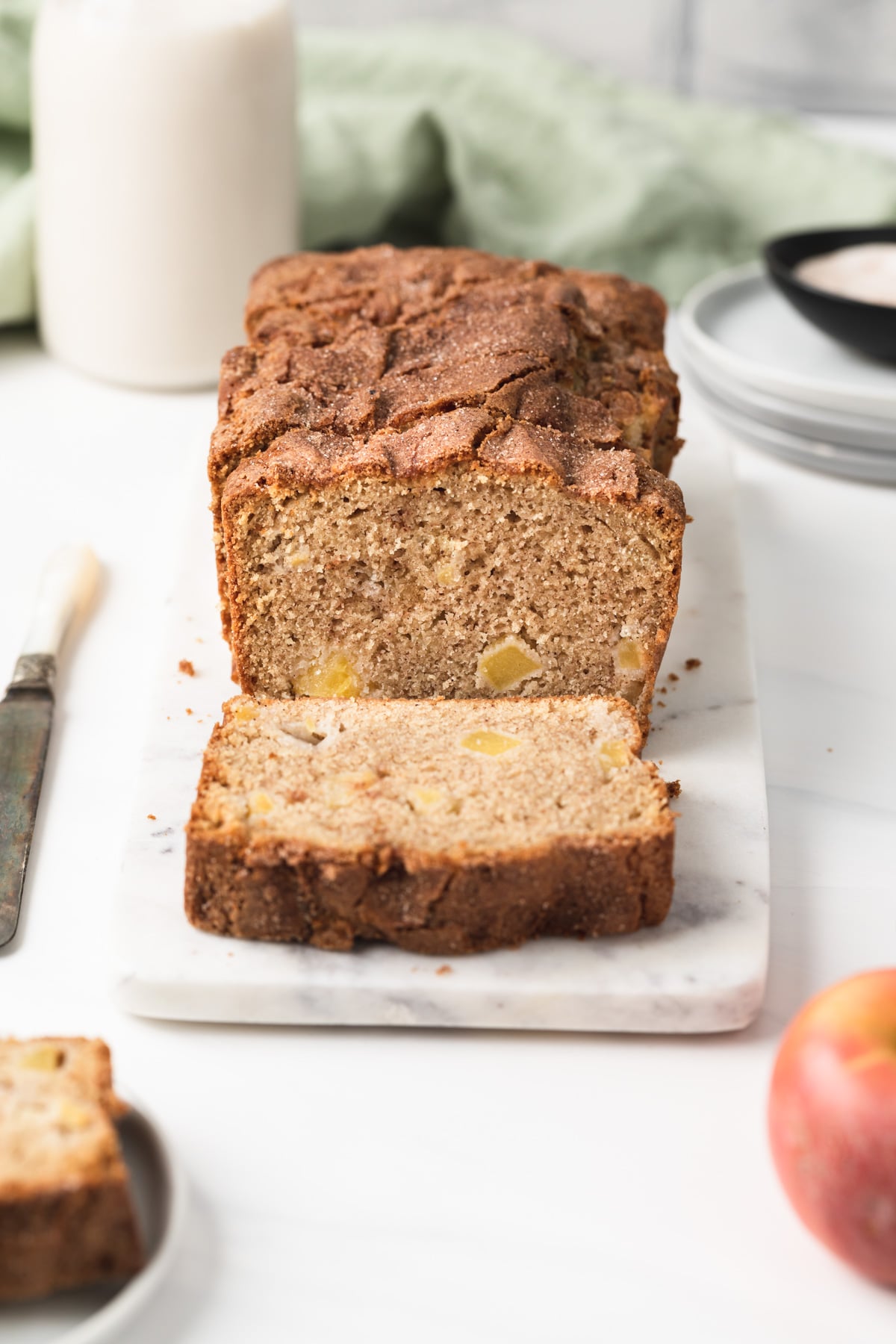 front view of apple bread with slice cut on marble slab