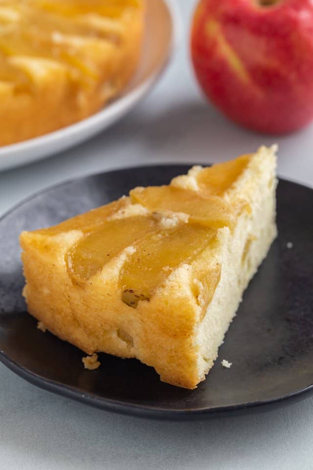 angled view of a slice of apple cake on a dark blue plate