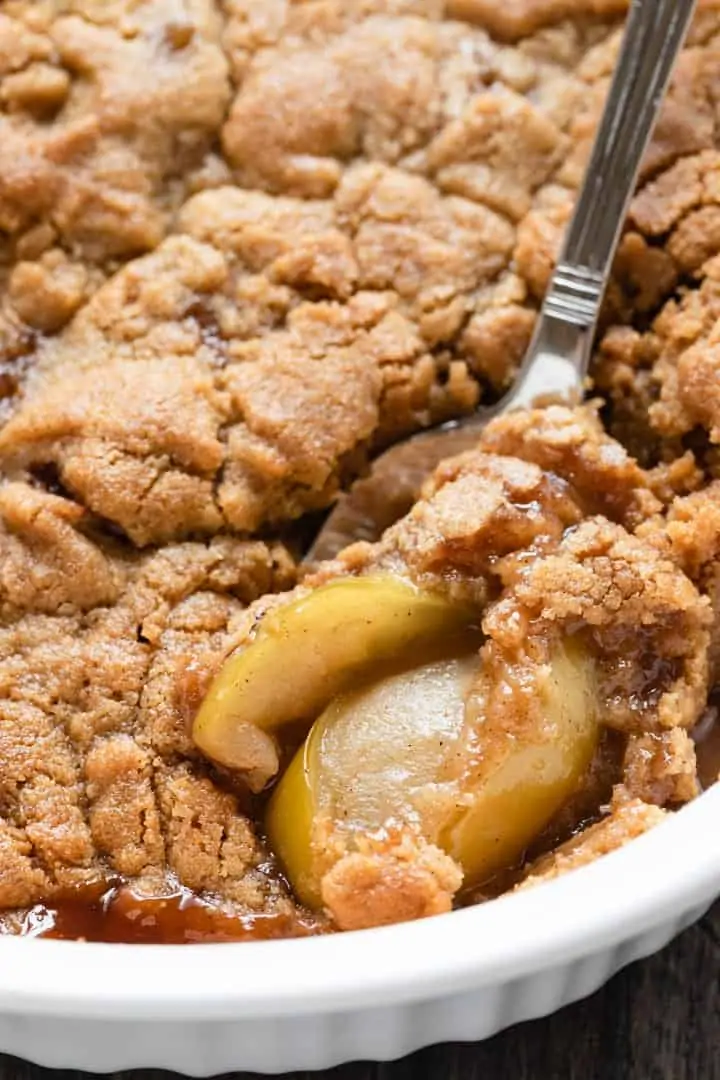 apple crumble in a casserole dish with a spoon scooping some out