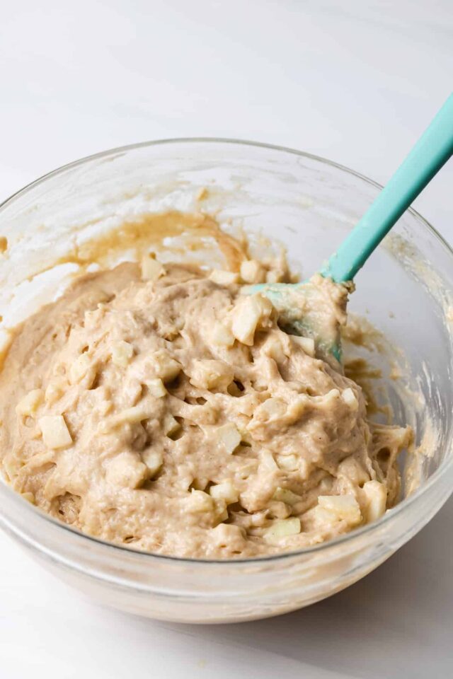 Chopped apples being stirred into muffin batter