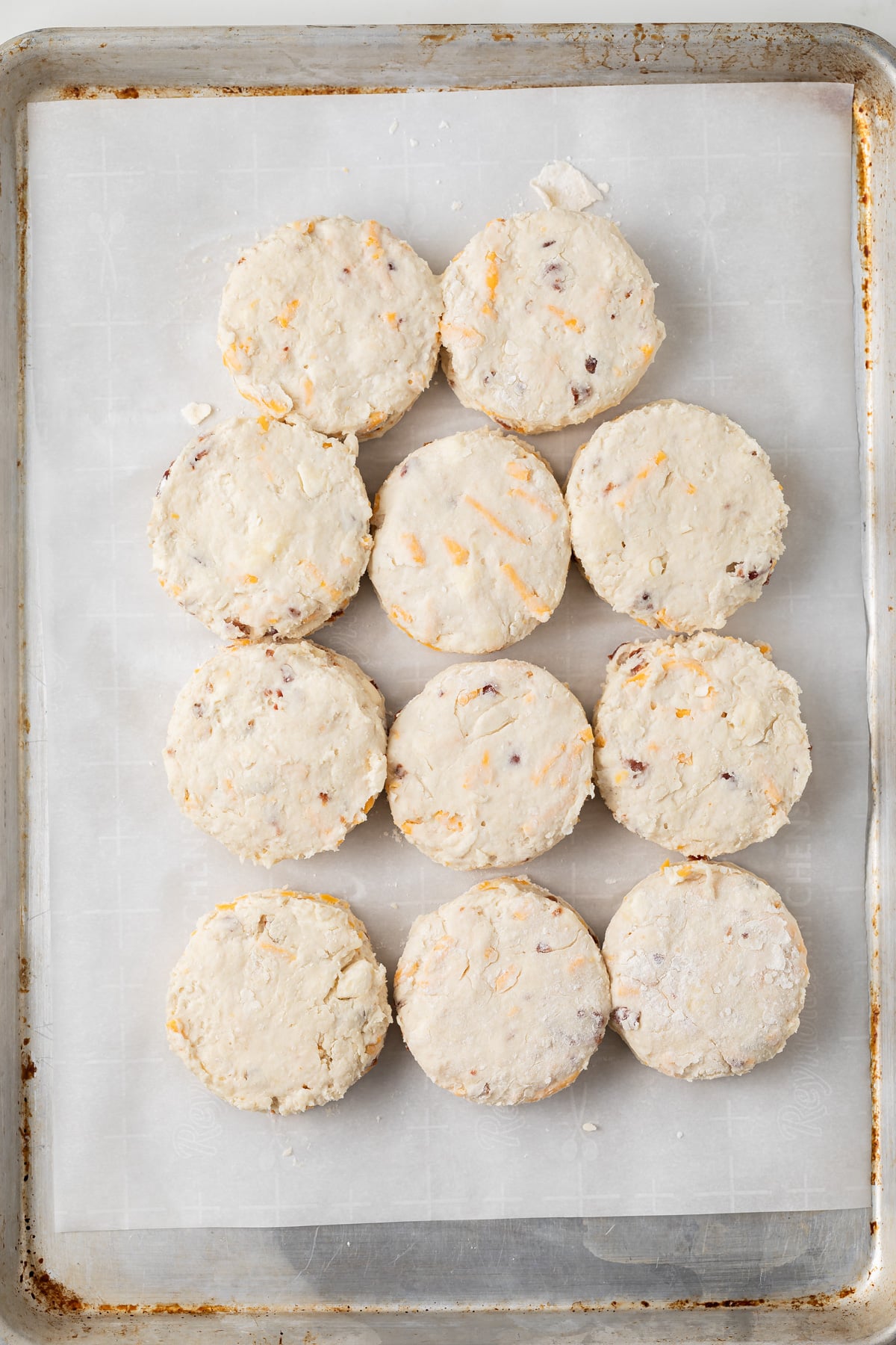 Unbaked bacon cheddar biscuits on a baking sheet.