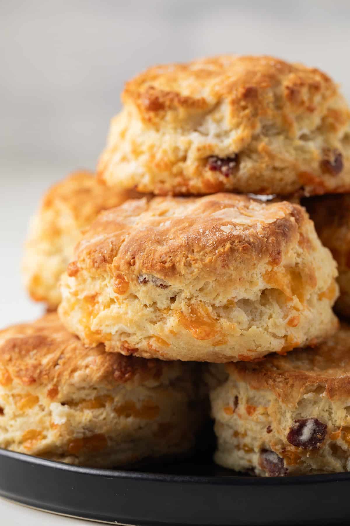 Bacon cheddar biscuits stacked on a plate.