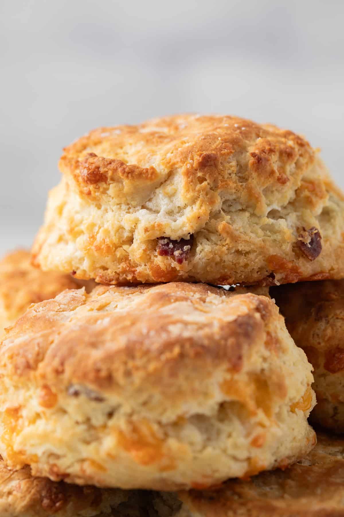Close up of bacon cheddar biscuits stacked on a plate.