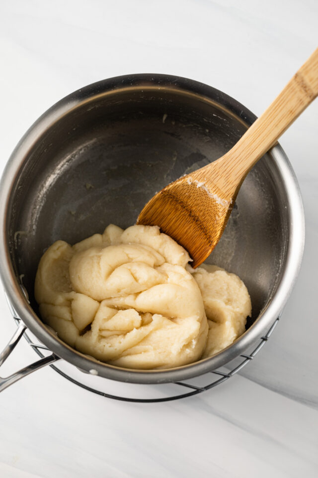 A wooden spoon stirring pate choux dough.