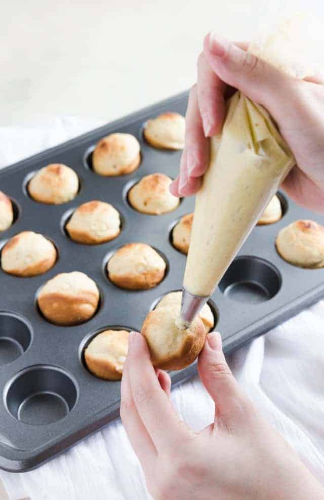 Baked bunuelos being filled with anise filling.