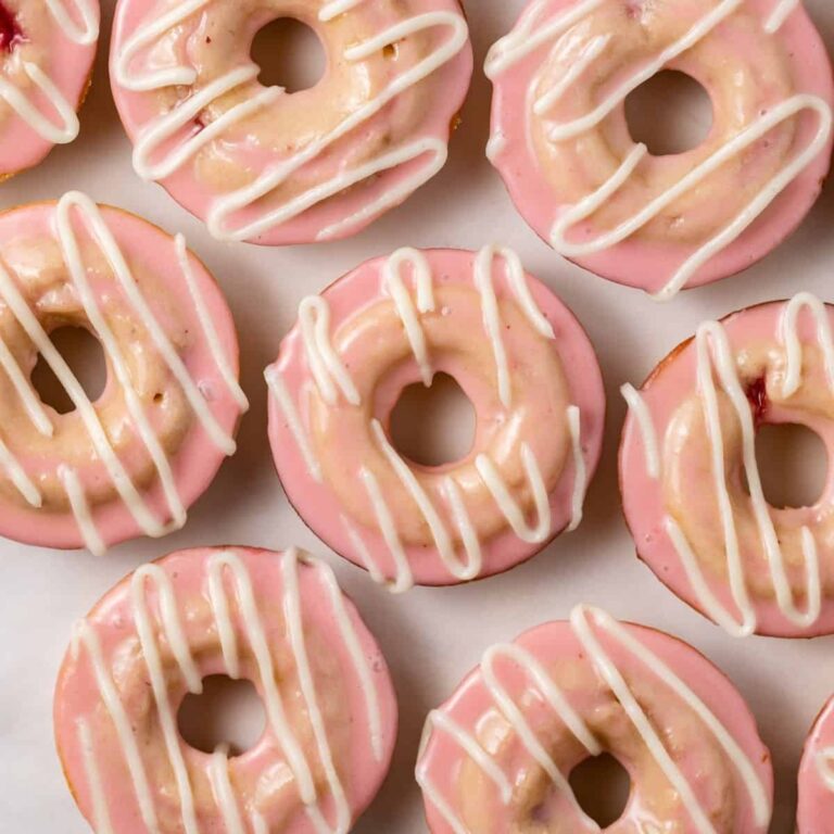 Baked strawberry donuts with frosting on white parchment paper