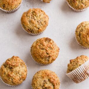 Banana Bran Muffins scattered on a white table top.