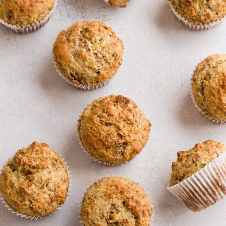 Banana Bran Muffins scattered on a white table top.