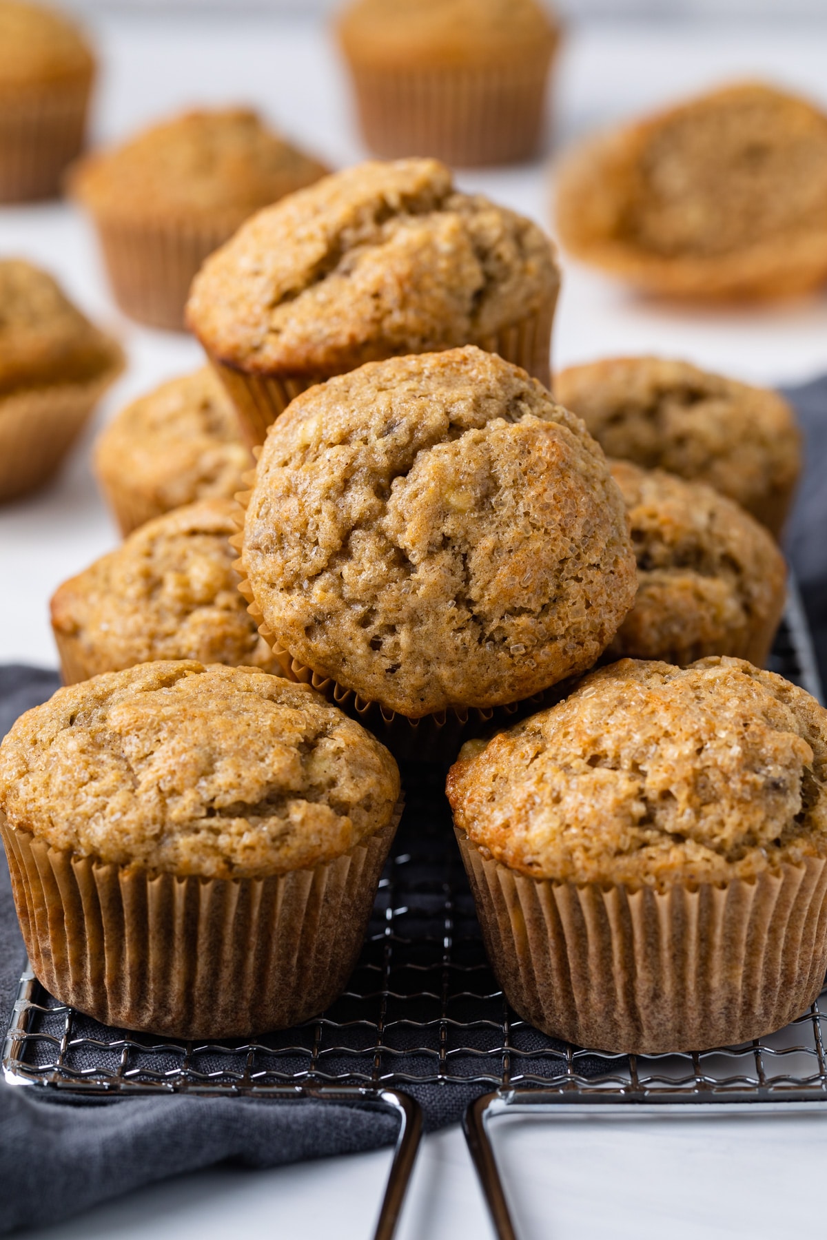 banana muffins piled on a wire rack with blue napkin