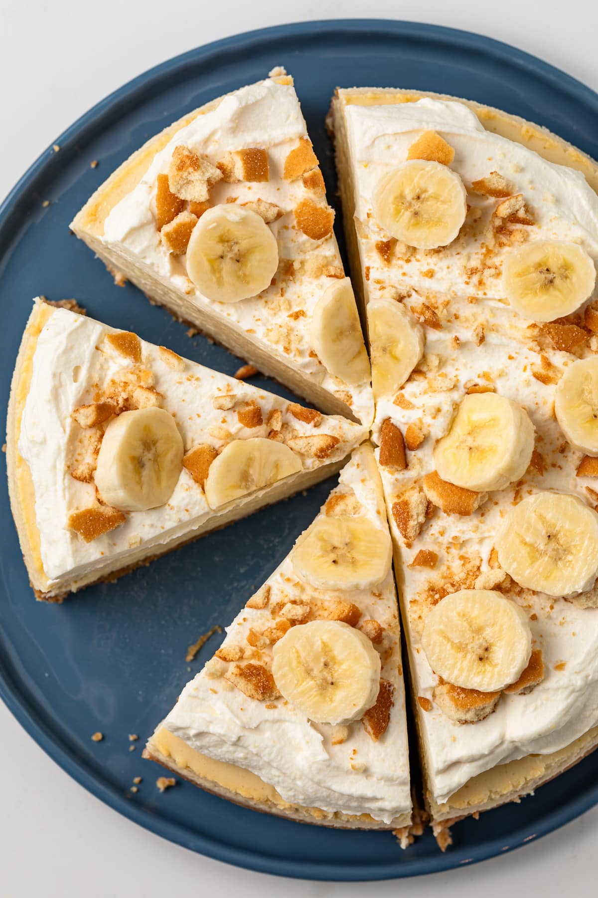 Sliced banana pudding cheesecake on blue serving plate.