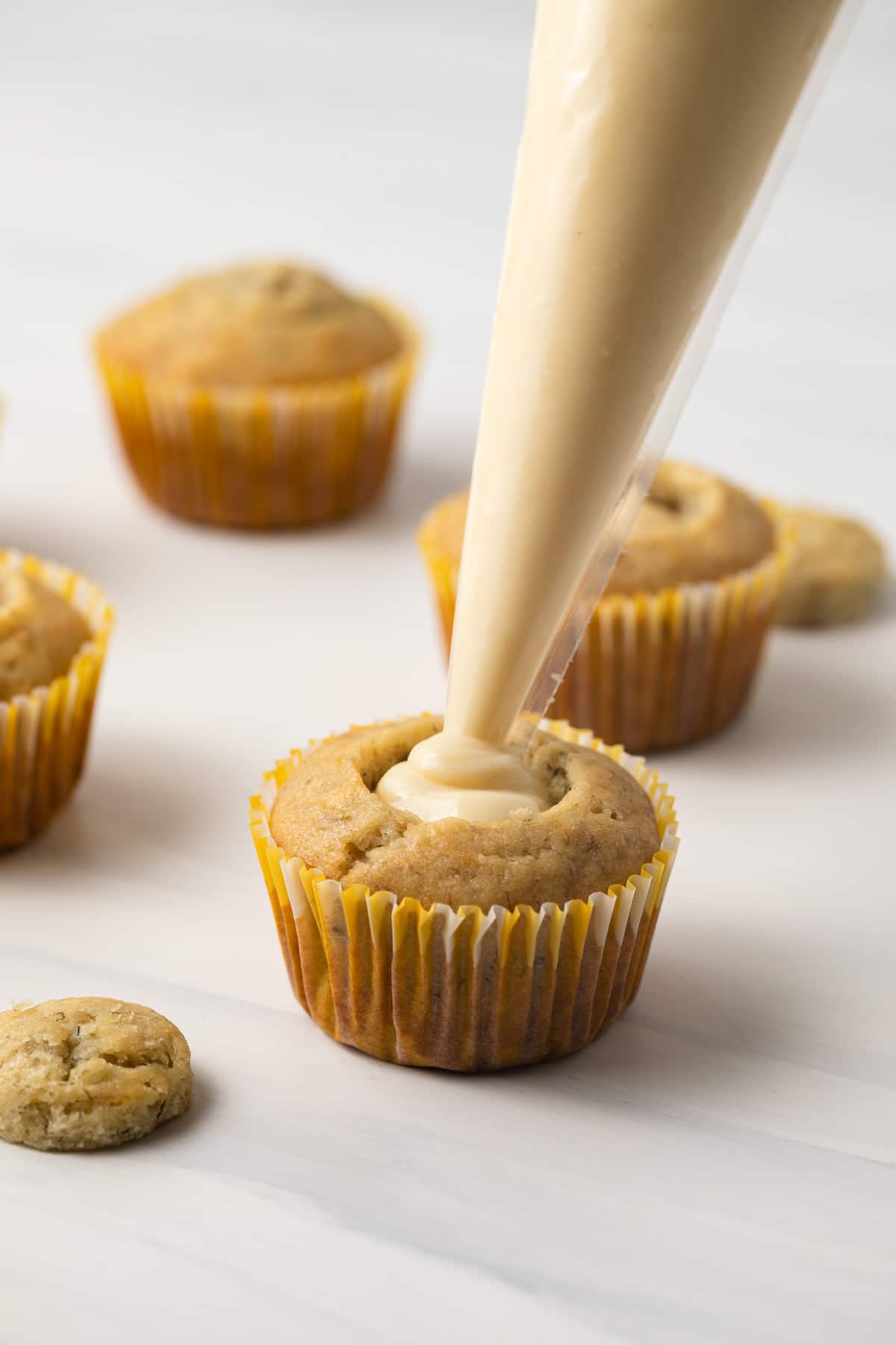 Piping vanilla pudding inside banana cupcakes.