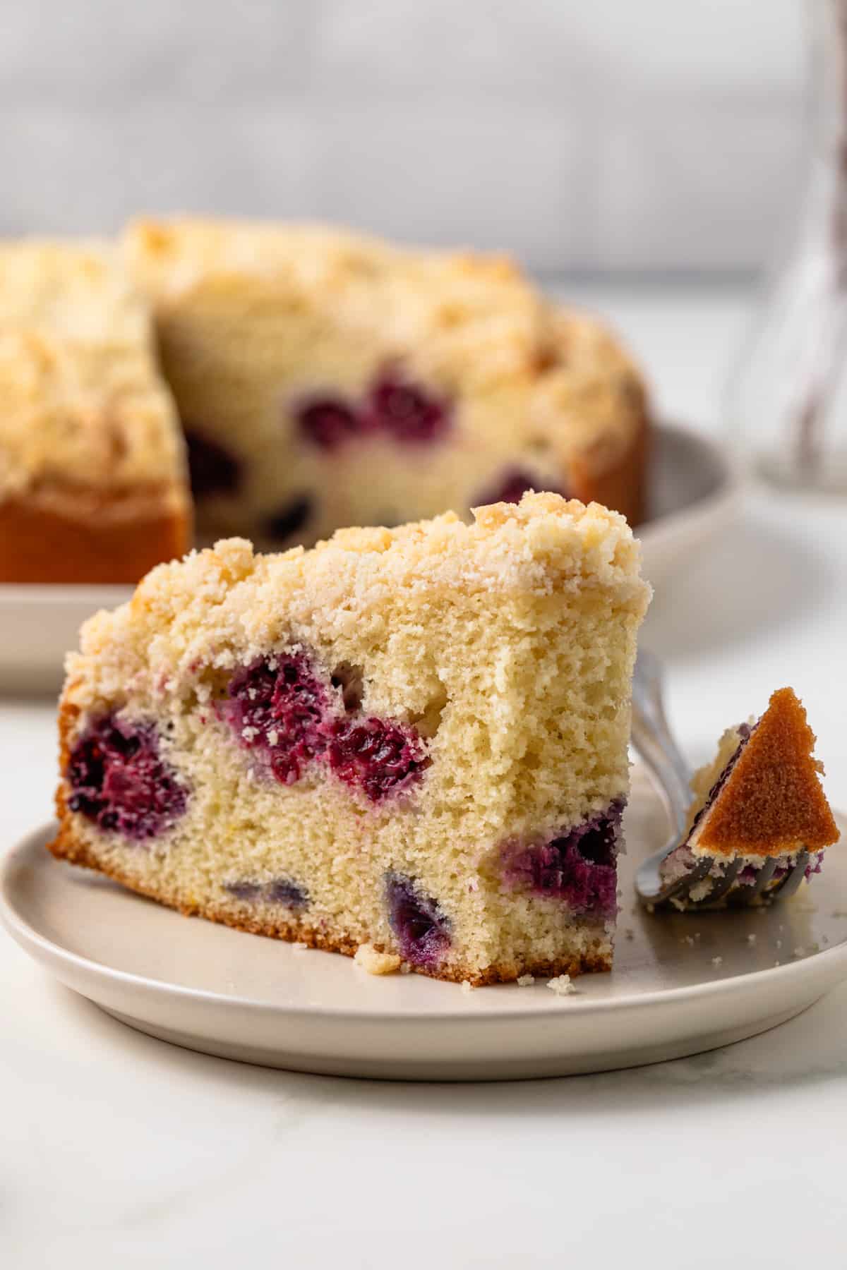 Slice of berry crumb cake with a bite taken out.