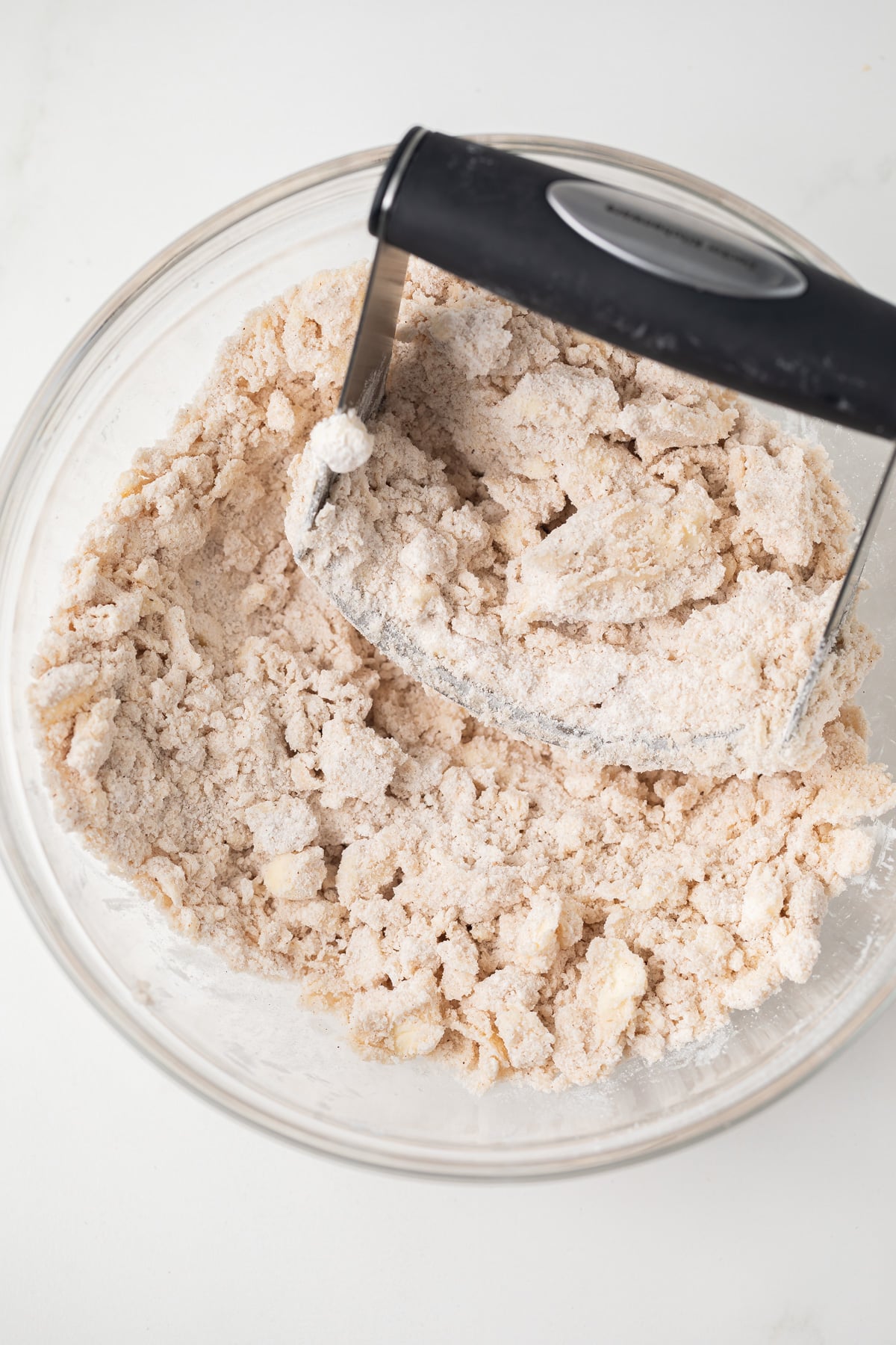 Butter cut into dry ingredients in glass bowl.