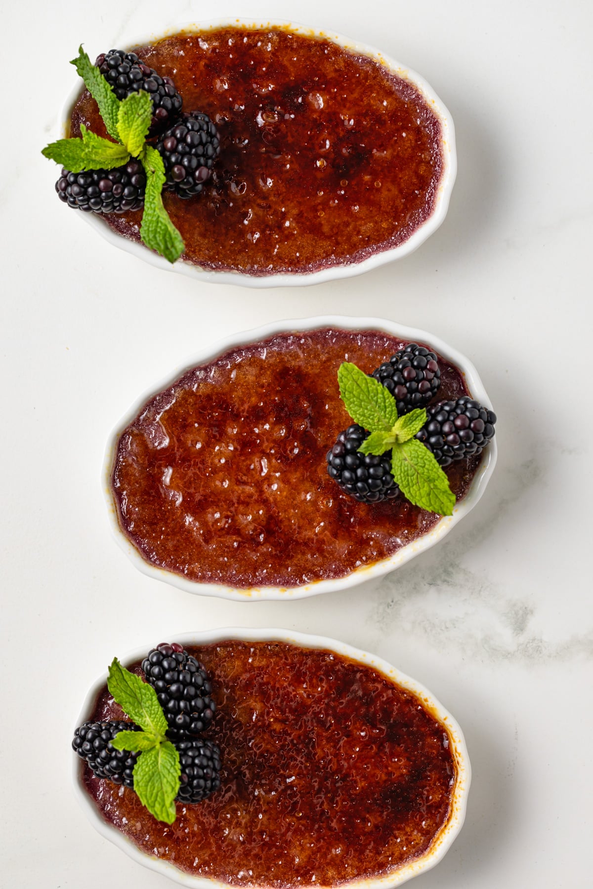Three ramekins of blackberry creme brulee.