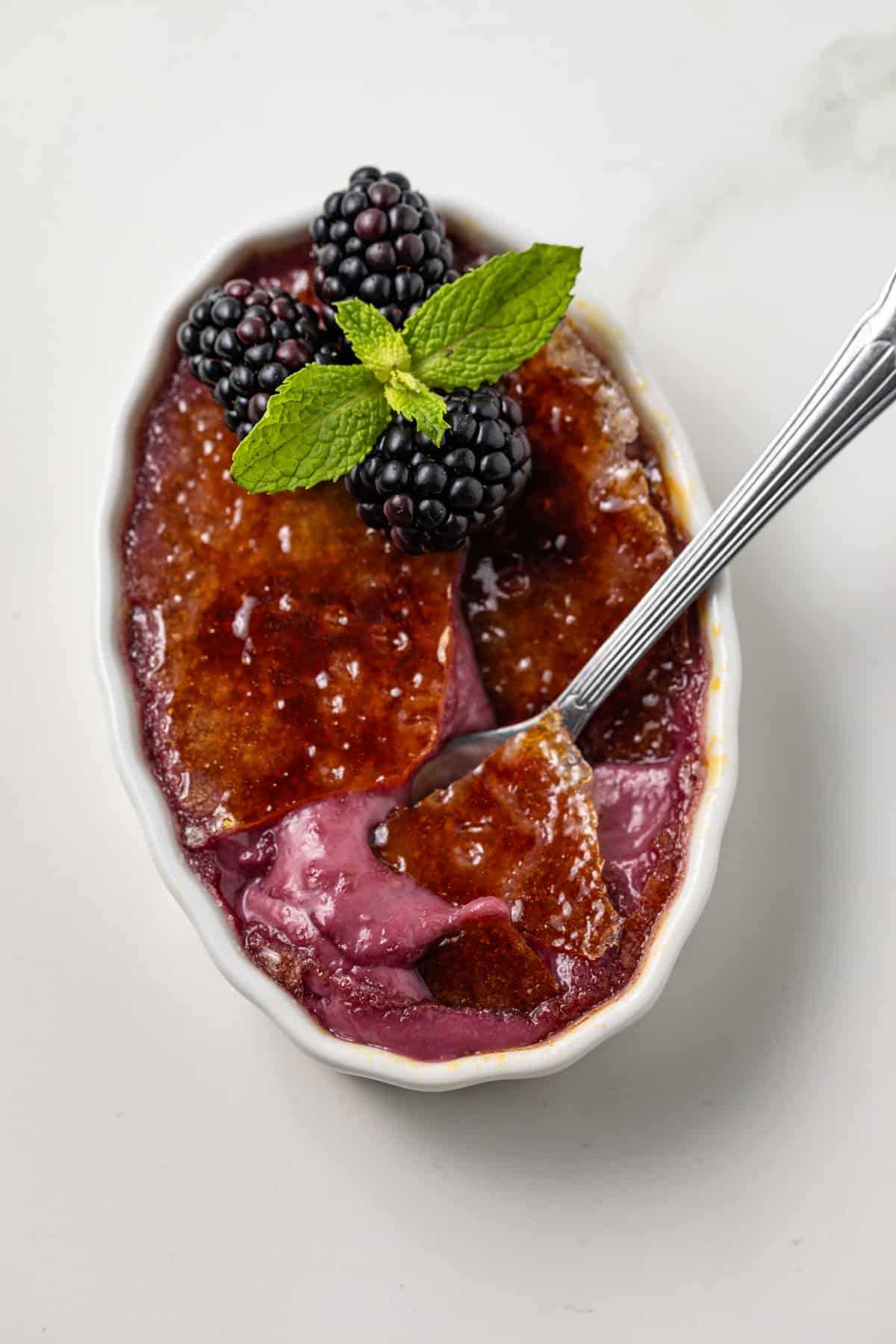 Spoon cracking through burnt sugar on creme brulee.