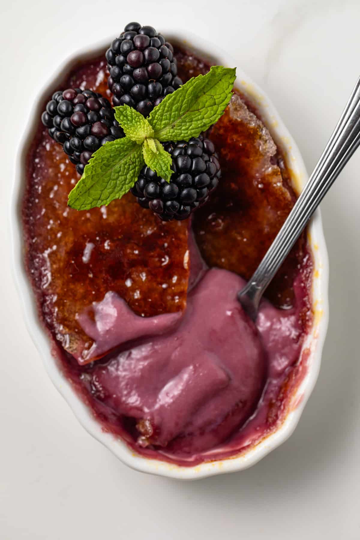 Spoon in blackberry creme brulee.