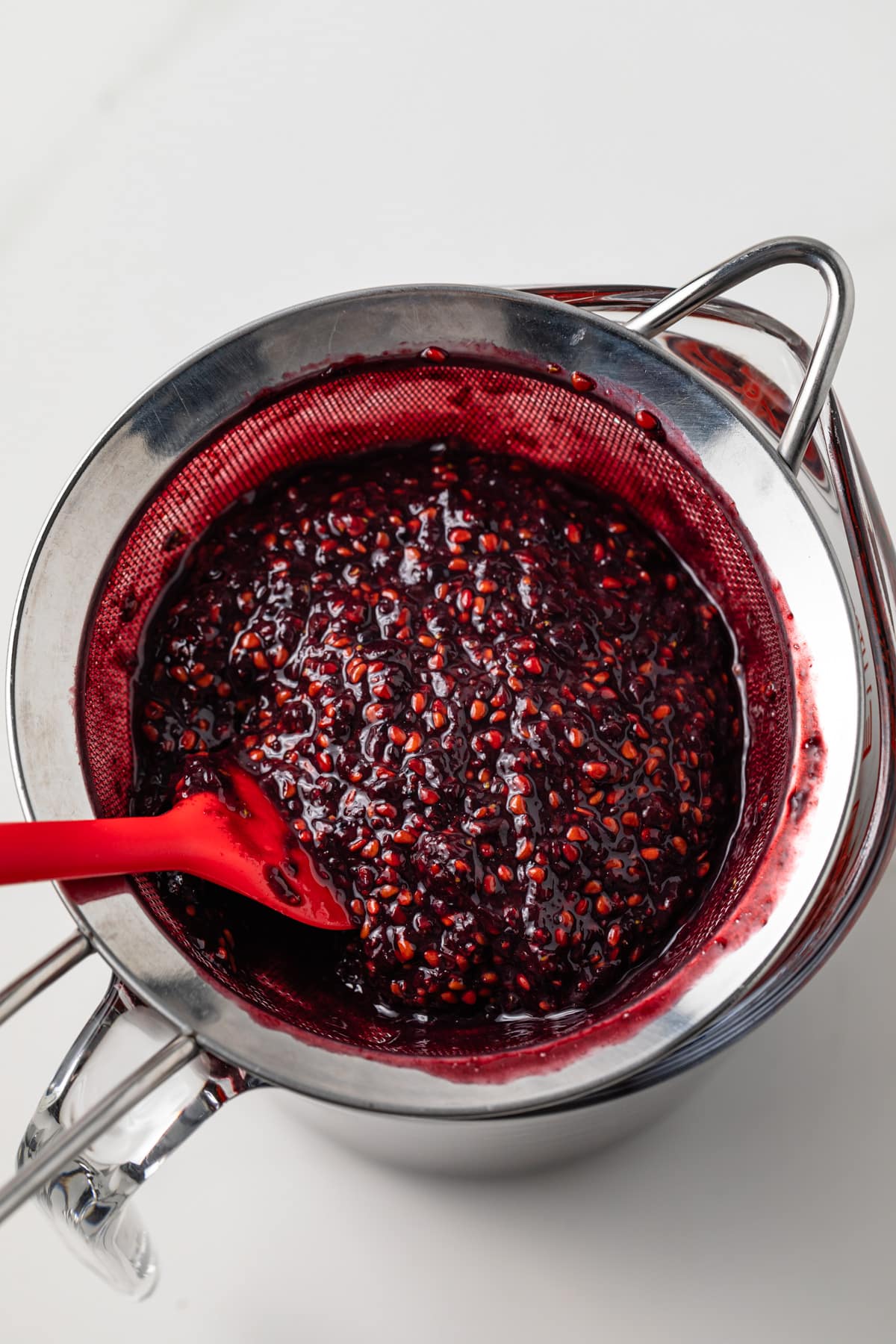 Blackberry pulp and seeds in mesh strainer.