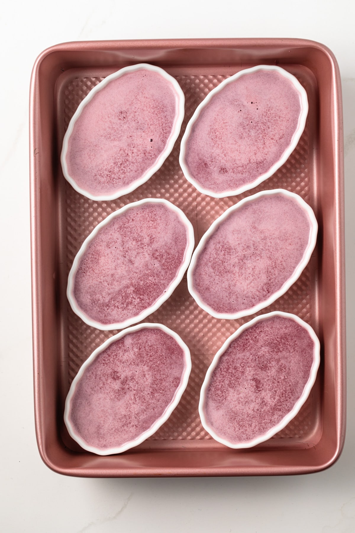 Unbaked ramekins of blackberry custard.