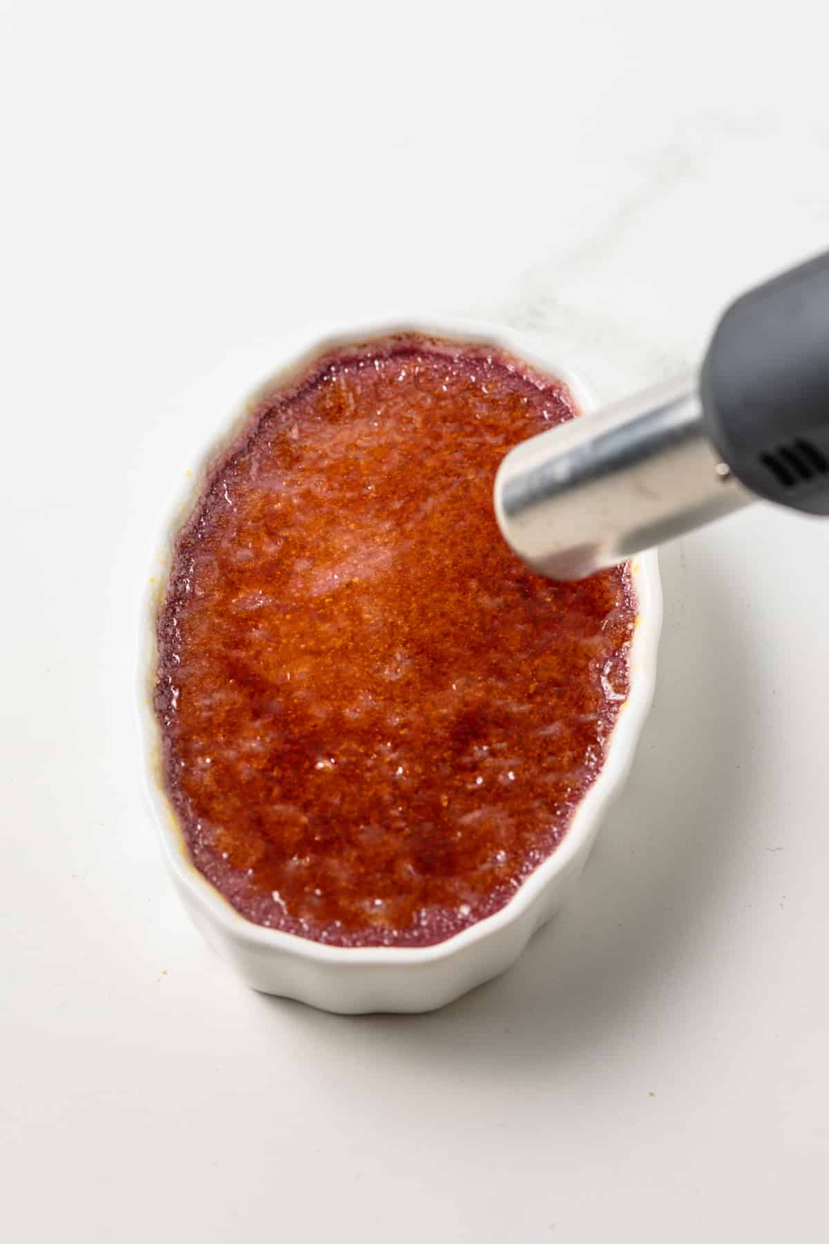 Torching sugar topping on creme brulee.
