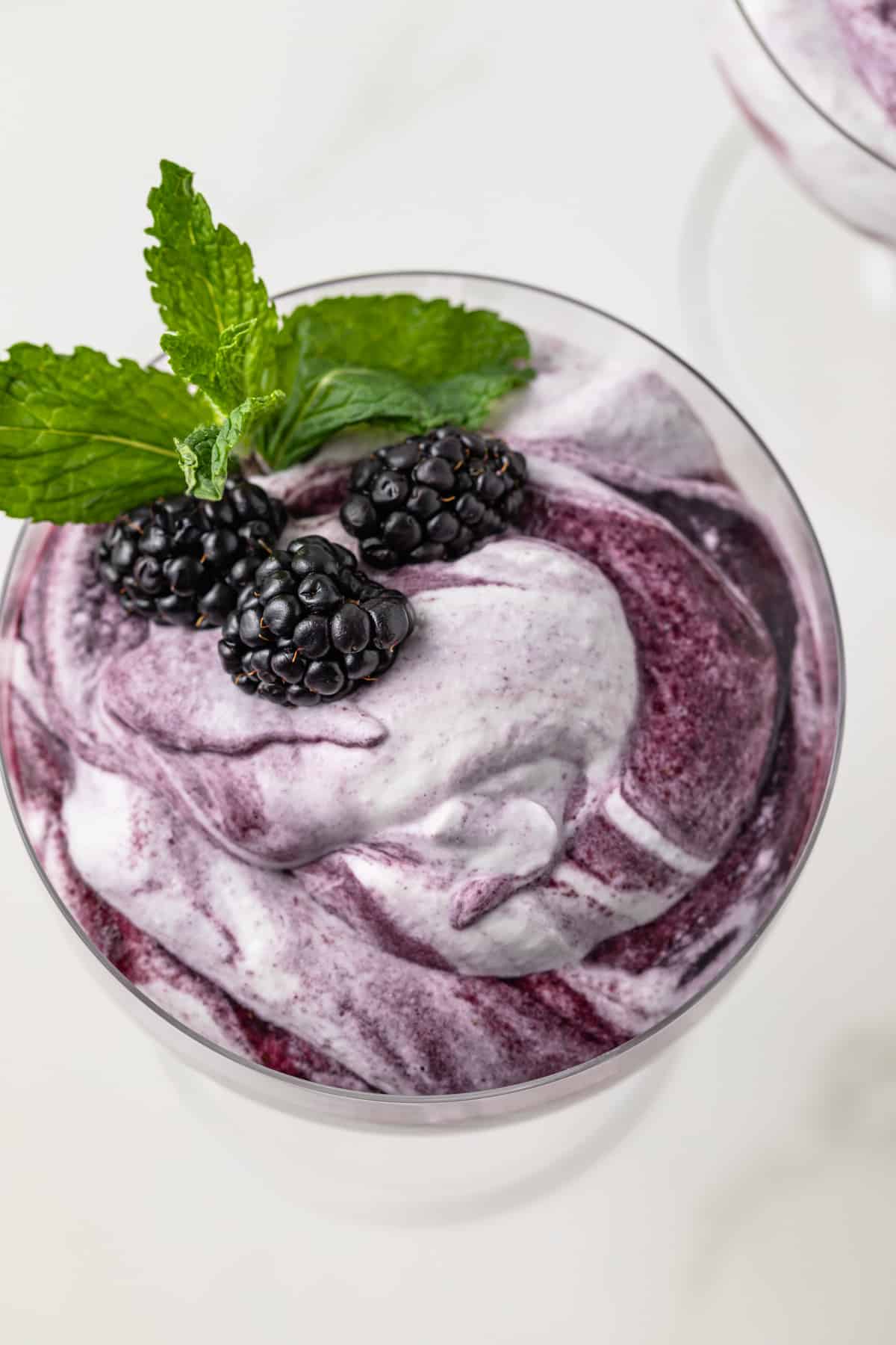 Overhead of blackberry fool in glass cup.