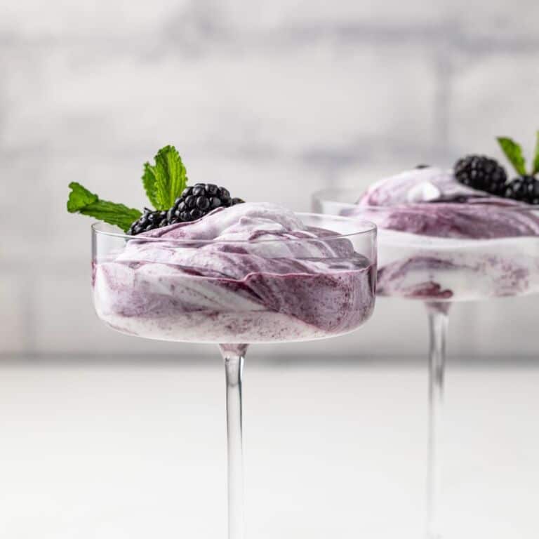 Side view of blackberry fool in glass cup.