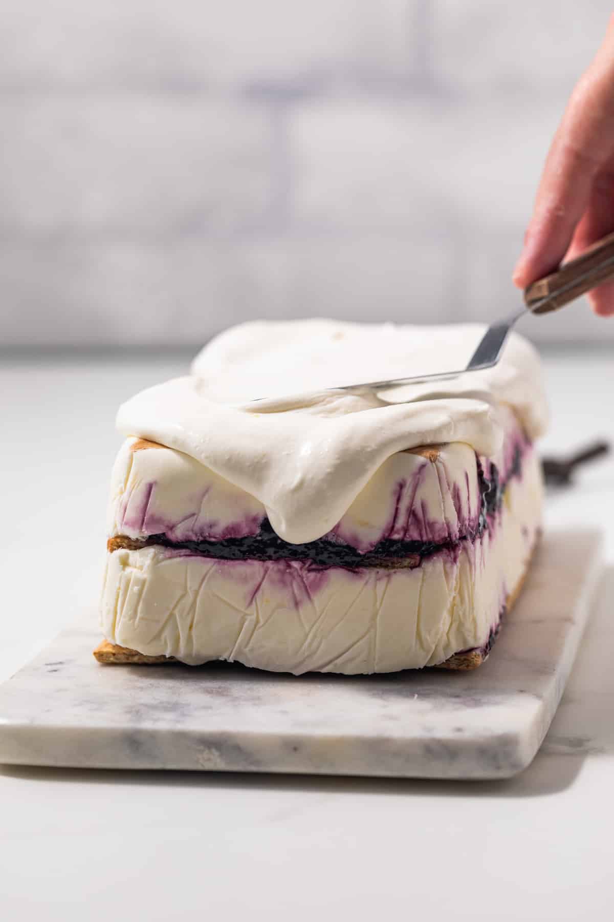 Lemon whipped cream being spread over icebox cake.