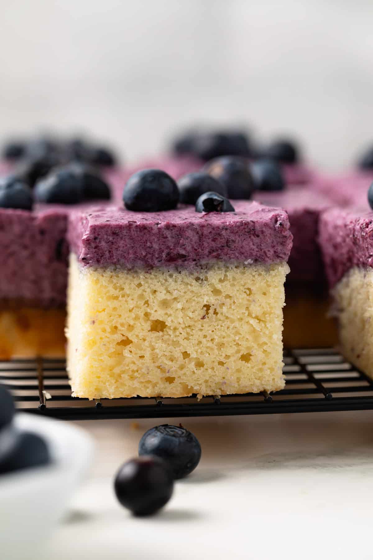 Slice of blueberry mousse cake on wire rack.