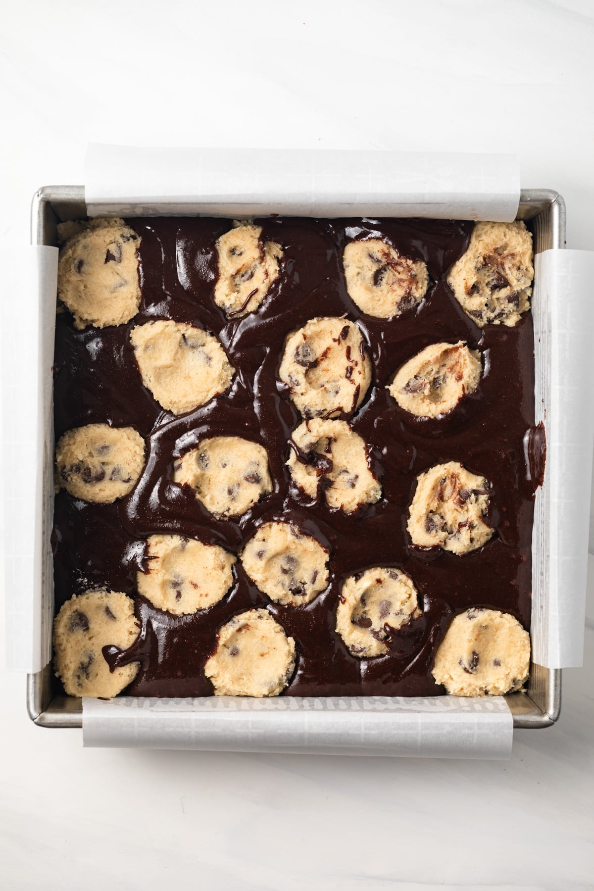 Unbaked cookie dough and brownie batter in a baking pan.