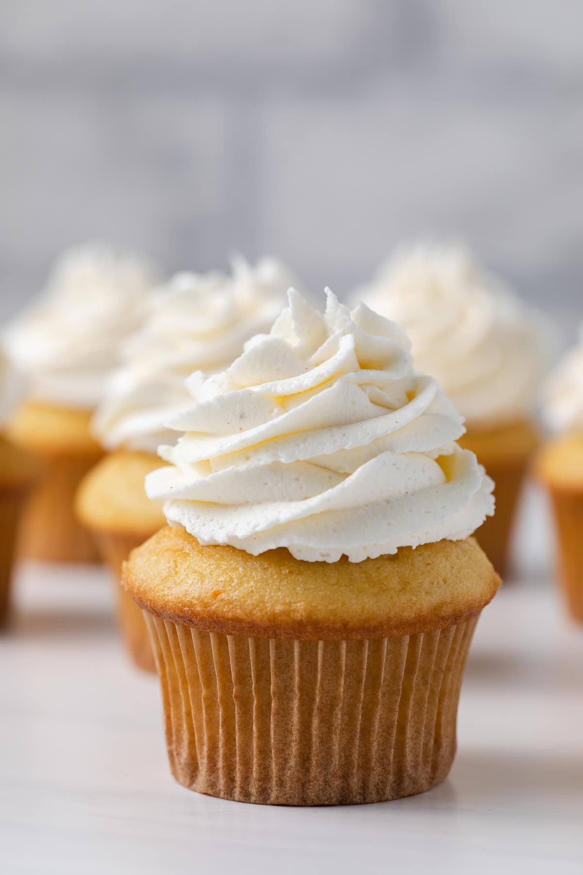 side view of yellow cupcake topped with a fluffy swirl of brown butter frosting