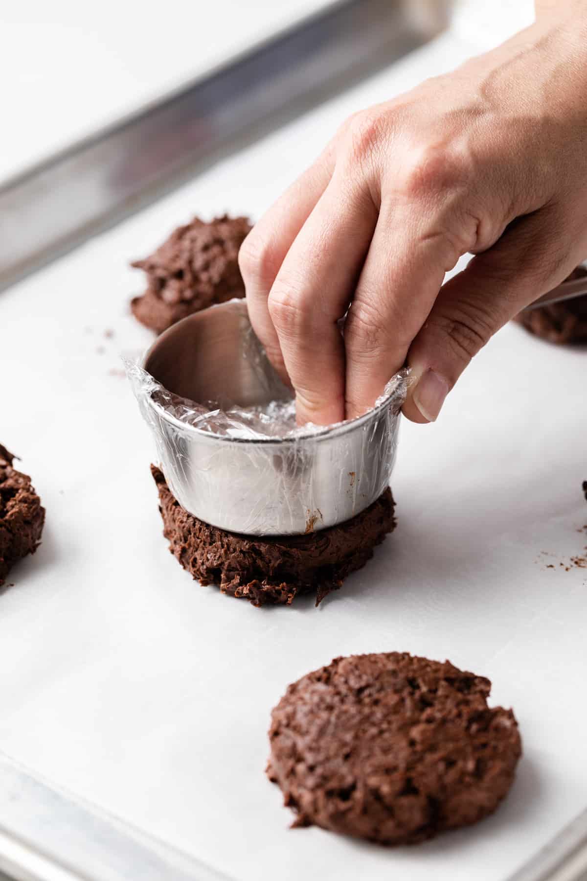 pressing cookie dough flat into disks with bottom of measuring cup