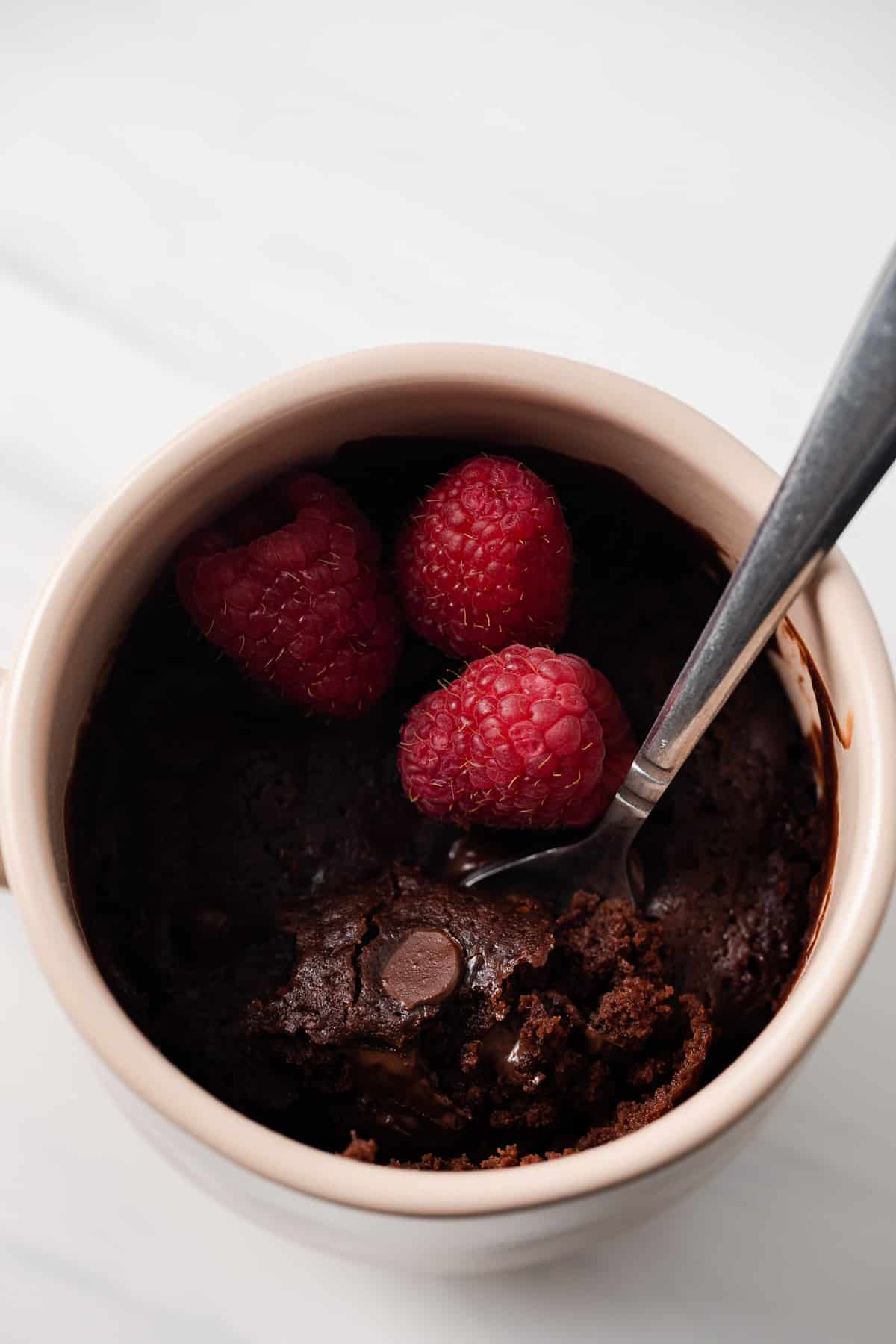 Brownie in a mug with a spoon taking out a bite.