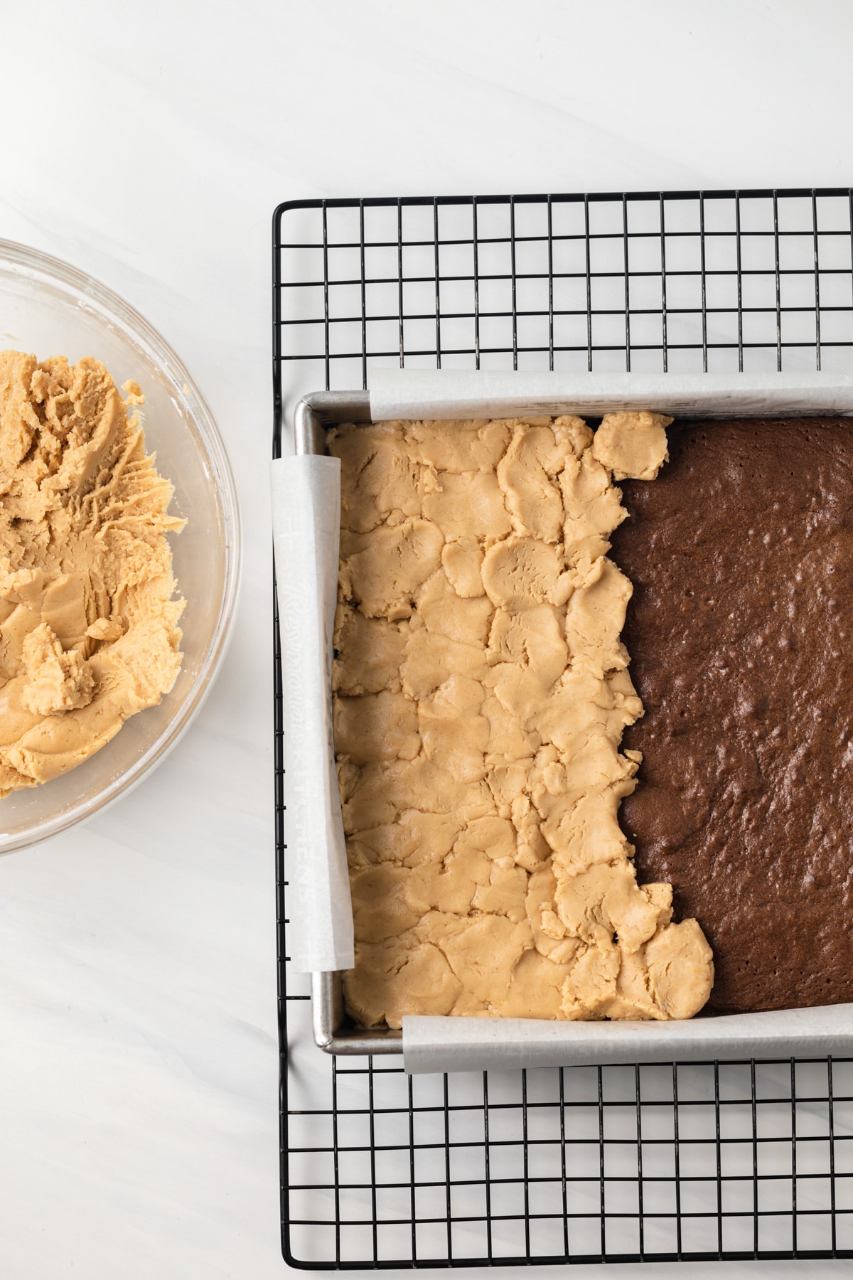 Peanut butter filling over brownies in a baking pan.
