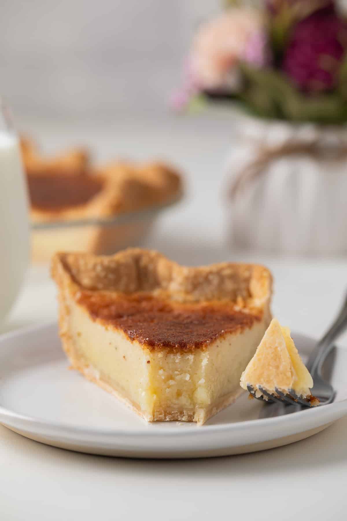 A bite taken out of a slice of buttermilk pie.