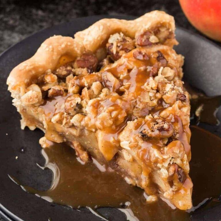 A slice of caramel apple pecan streusel pie on a black plate.