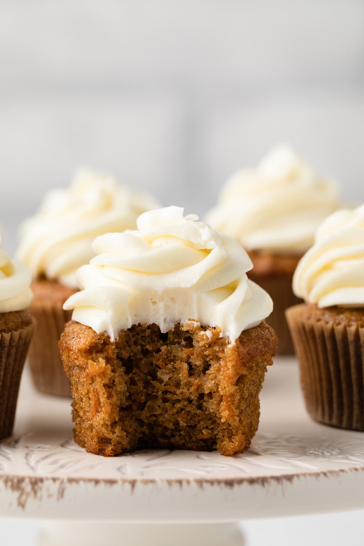 Carrot cake cupcake with a bite taken out.