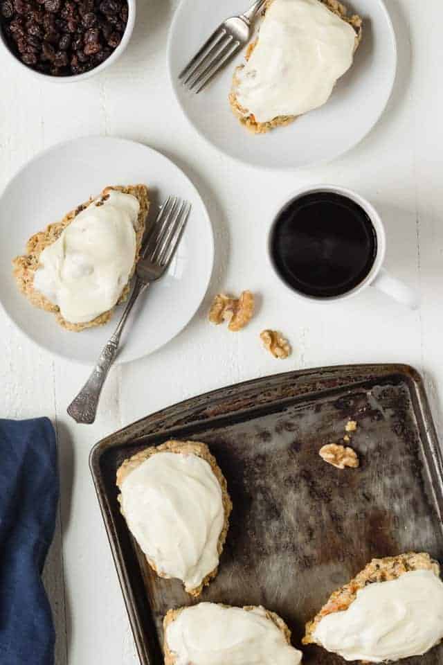 Overhead view of Carrot Cake Scones on white plates and a baking sheet.