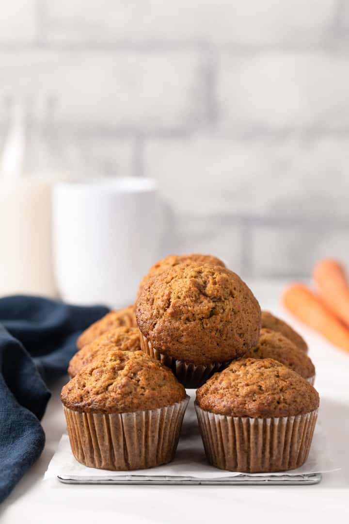 Carrot muffins stacked on small wire rack.