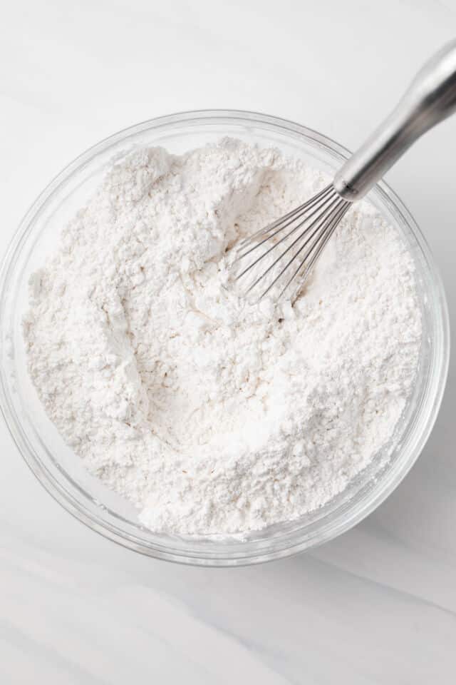 Dry ingredients mixed in glass bowl with a whisk.