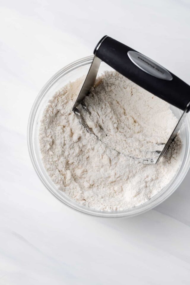 A pastry cutter cutting butter into dough