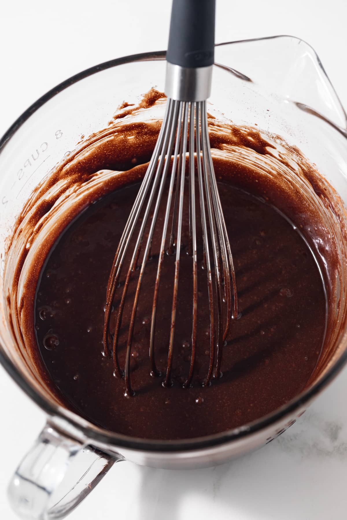 Wet ingredients with chocolate mixed in glass bowl.