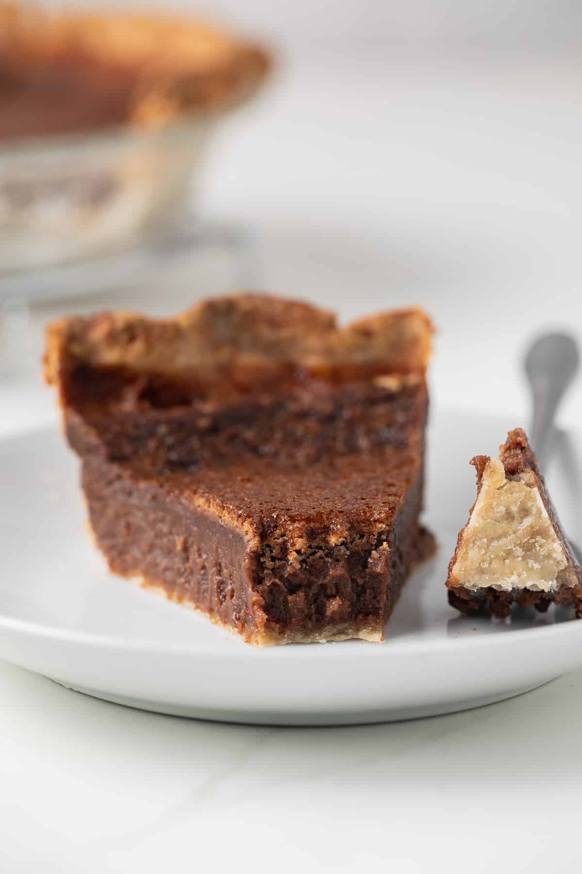 Slice of chocolate chess pie with a bite taken out.