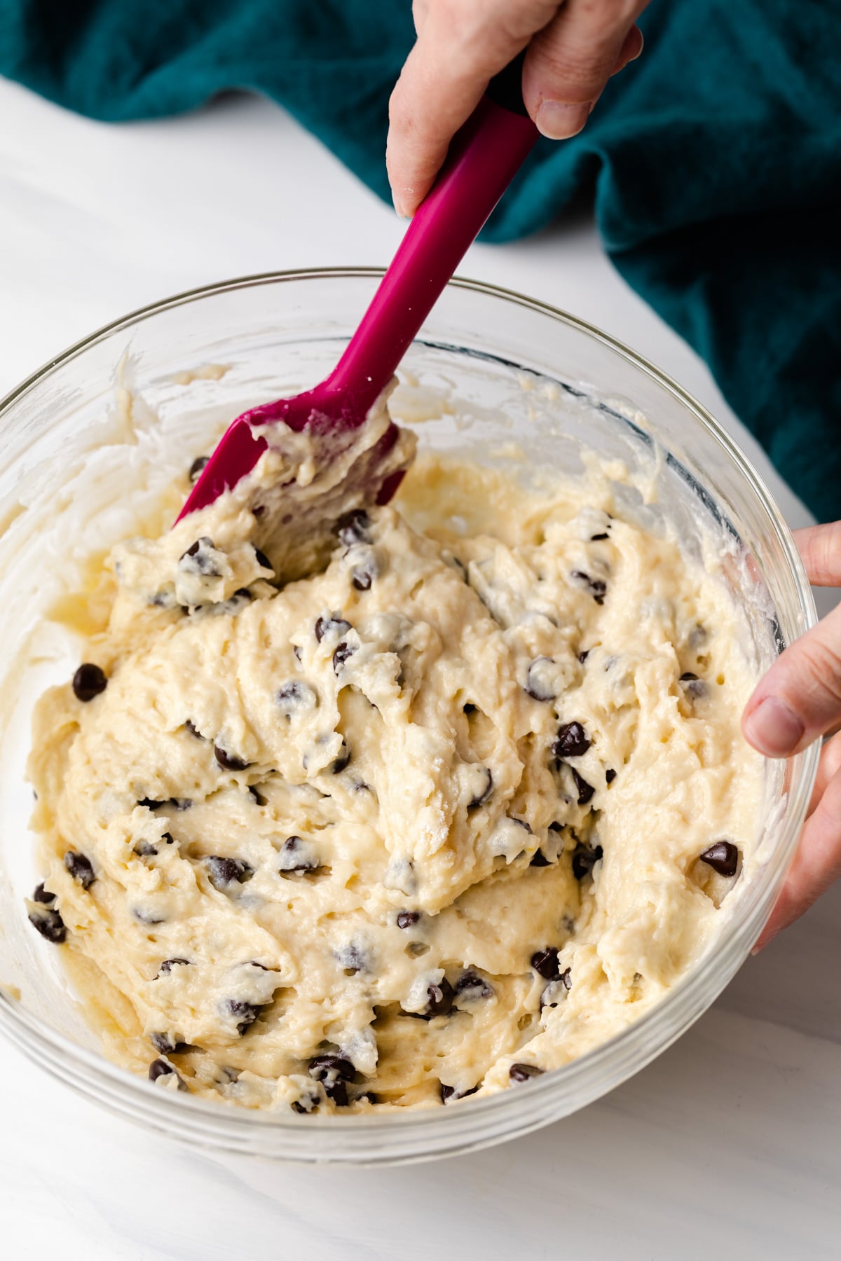 chocolate chip muffin batter in glass bowl with pink spatula