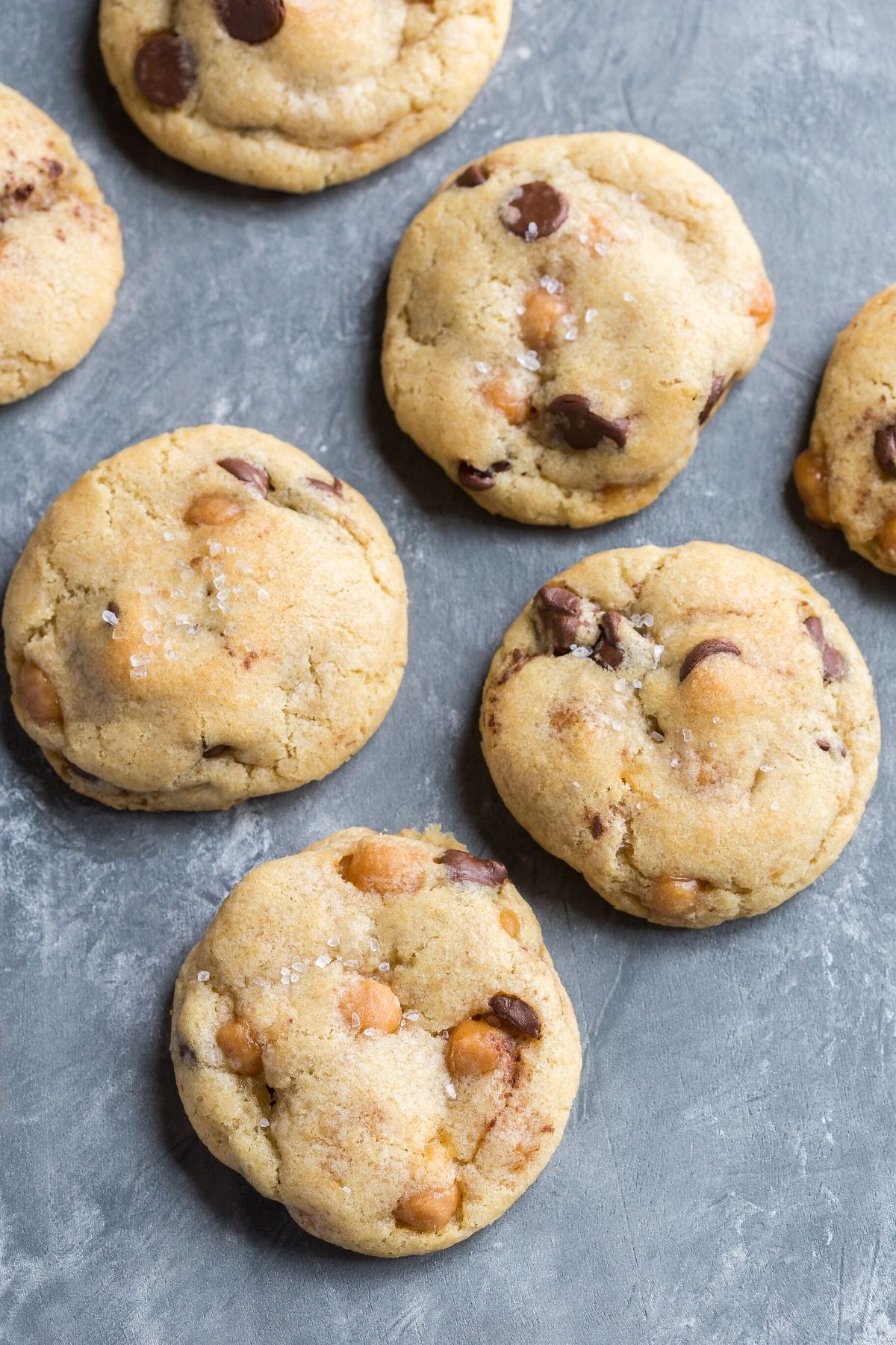 Overhead view of Soft and chewy Chocolate Chip Salted Caramel Cookies on a grayish blue background.