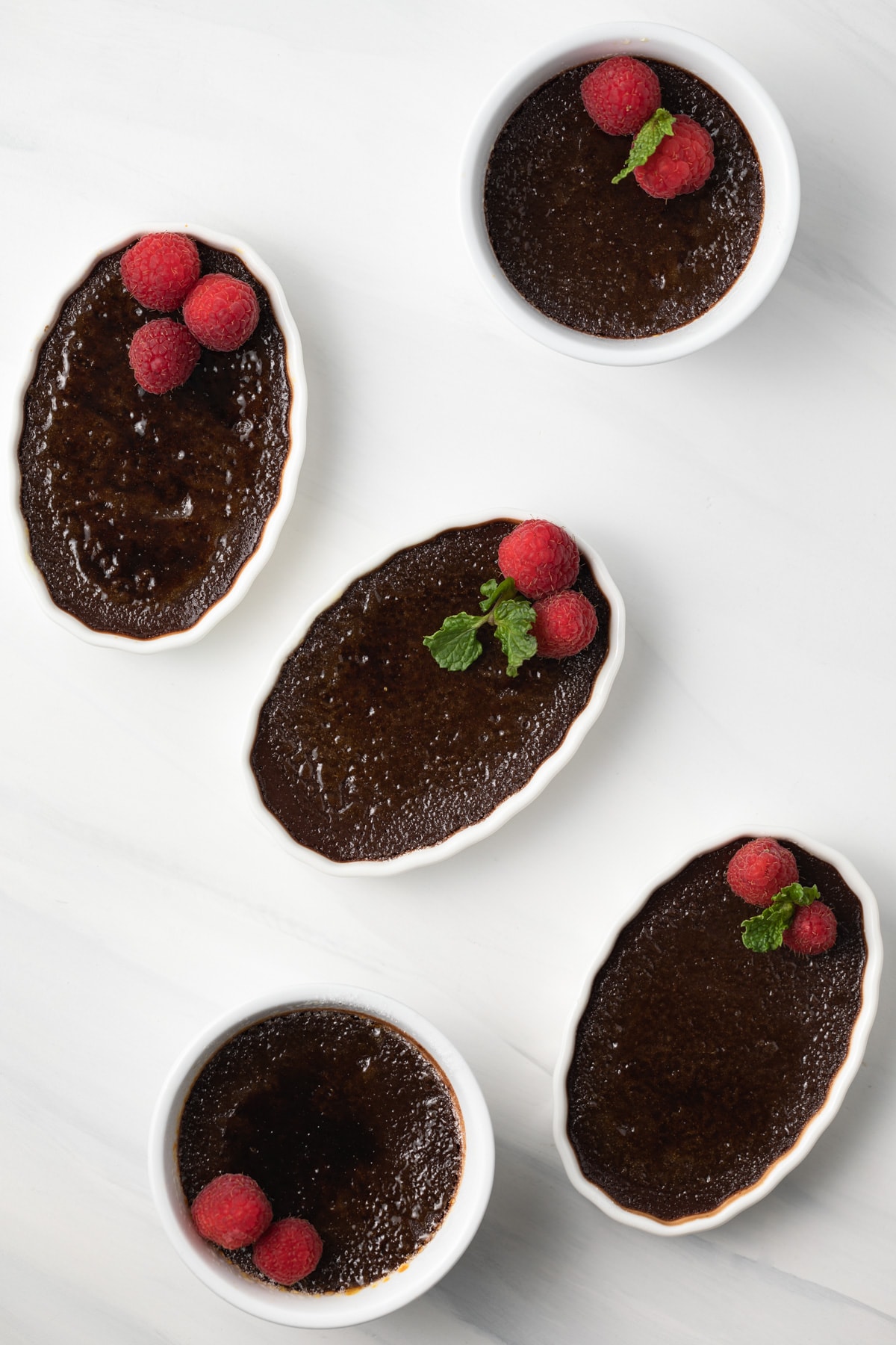 Overhead of chocolate creme brulee in white ramekins.