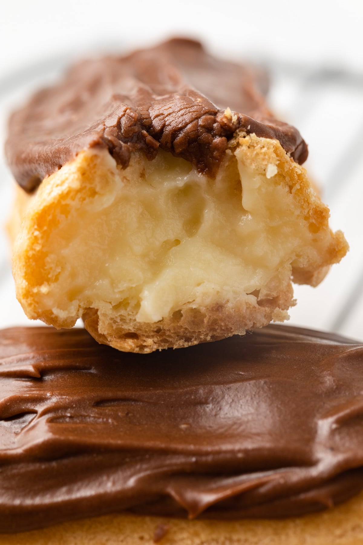 Close up chocolate eclair with bite taken out.